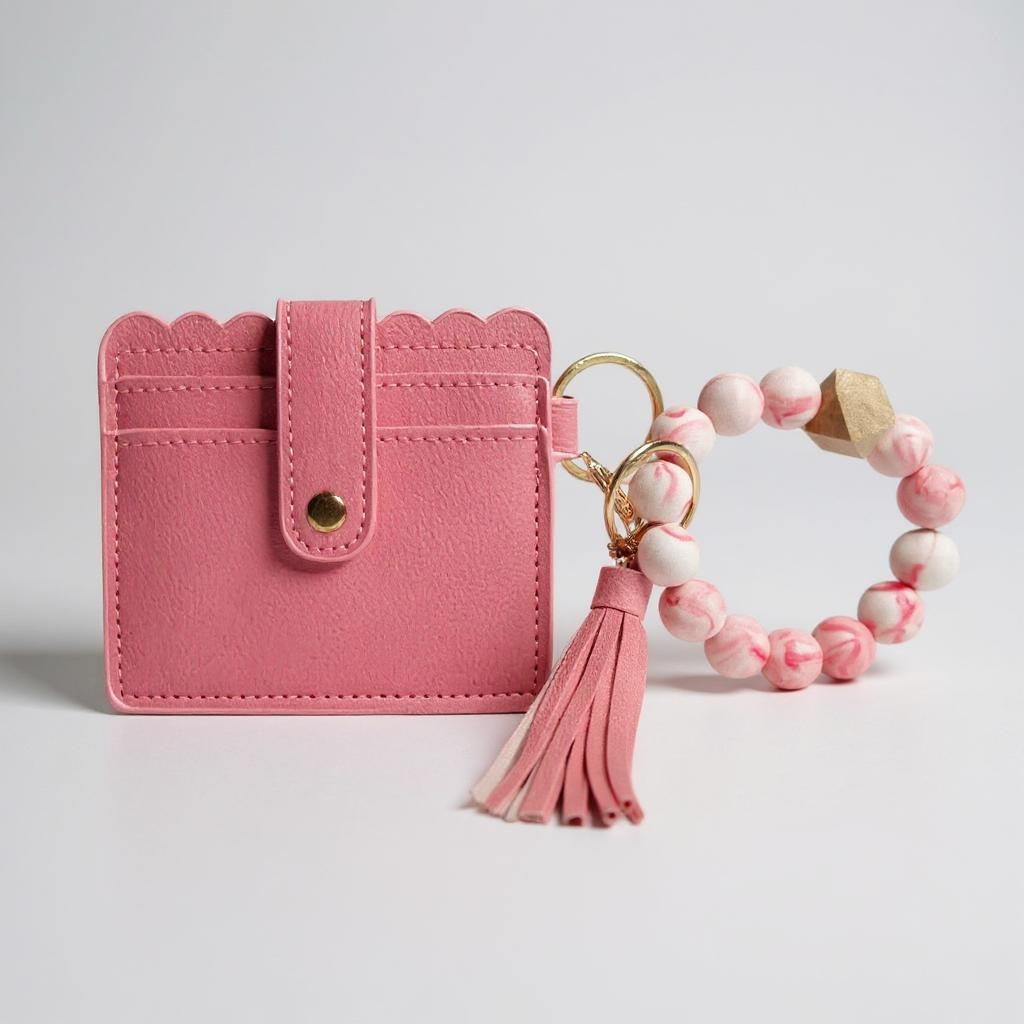 Pink scalloped-edge cardholder with tassel keychain and pink beaded bracelet 